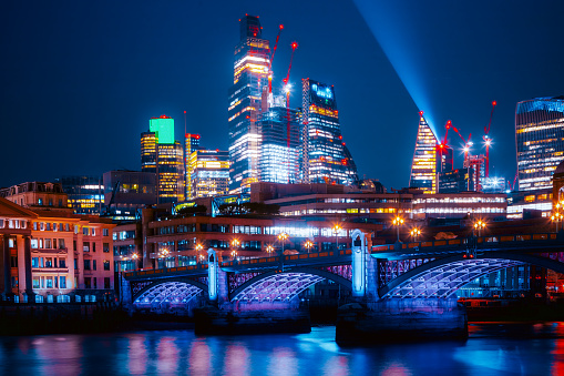 Panoramic view of The City of London cityscape skyline with Blackfriars Bridge and metropole financial district modern skyscrapers after sunset on the night with illuminated buildings with Thames river and cloudy sky in London, UK