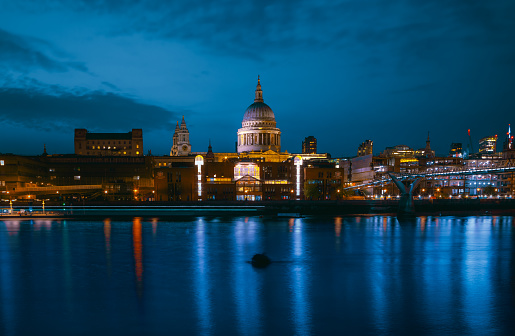 Long exposure shot of St Paul's Cathedral and Millennium Bridge in London at night after sunset with reflections in River Thames in London City, England, United Kingdom
