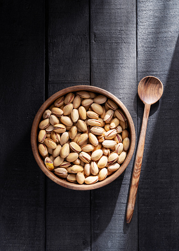 Pistachios in bowl on black wooden background