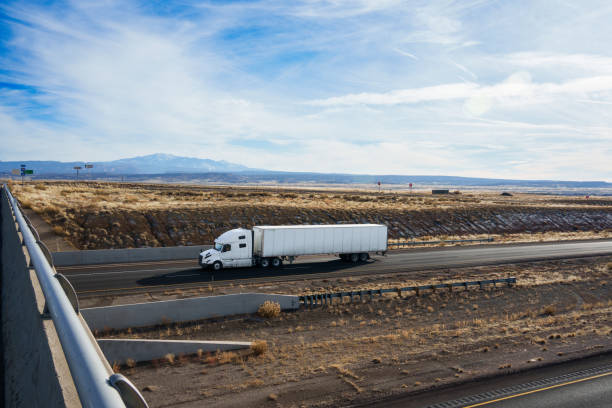 istock Brightly Colored White Semi-Truck Traveling Down I-70 in Eastern Utah Desert 1975719084