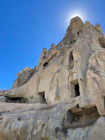 exterior of the rupestrian church carved in stone, in the open air museum of Goreme, Cappadocia, Turkey, with the sun rising from behind, vertical