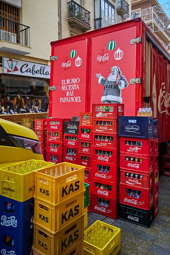 Sevilla, Spain - January 04, 2024: Coca-Cola delivery truck picking up empty bottles. Boxes of empty bottles stand on the street in front of the truck.