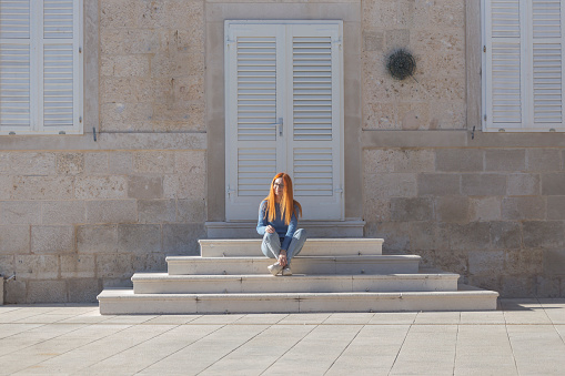 Tourist enjoy sunny day sitting on stairs in front of entrance door of  house in old medieval city of Dubrovnik