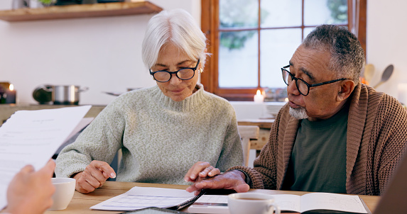Couple, paperwork and reading for insurance in retirement, planning and bills or documents. Senior people, marriage and communication or discussion for future, saving and finance in kitchen at home