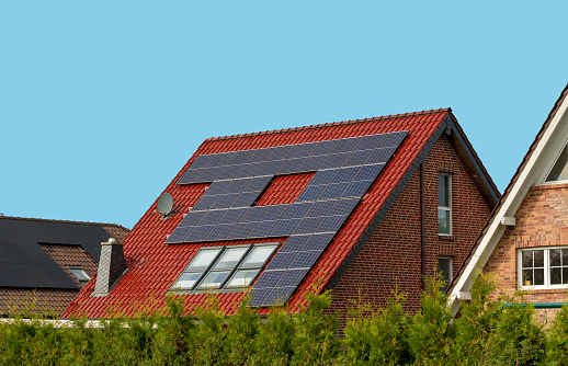 View of residential cottages with a solar photovoltaic system on a tiled roof. Renewable ecological green energy production concept. Solar panels.
