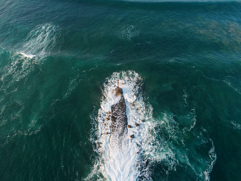 A breakwater with a small lighthouse as seen from above