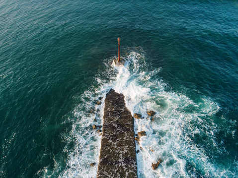 A breakwater with a small lighthouse as seen from above