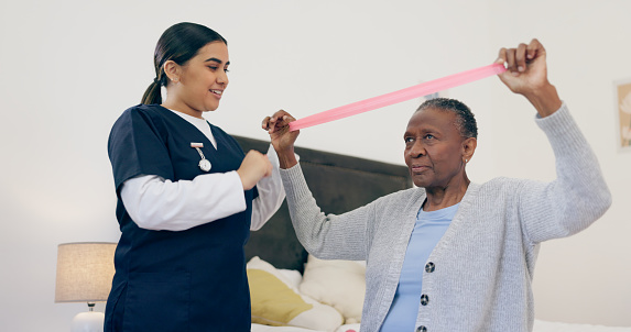 Senior woman, caregiver and band for exercise in house, physiotherapy help or wellness workout support. Nurse, elderly patient or healthcare in retirement, trust or physical therapy for health body