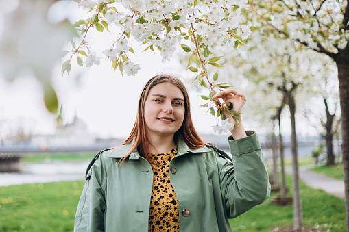 Young woman enjoying scent in blooming spring garden. Young woman enjoying scent in blooming spring garden. Spring girl photo, woman at sakura flowers background. Hanami celebration concept