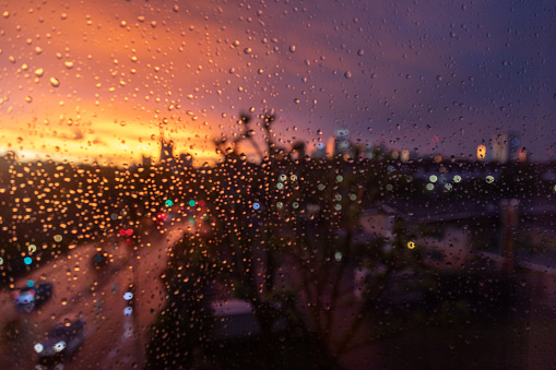 Capturing the essence of city life with evening road traffic and rain streaks down the window, creating an artistic veil over the vibrant London cityscape. The dance of raindrops against the glass harmonizes with the warm hues of a sunset, offering a unique and captivating perspective on the beauty of urban living