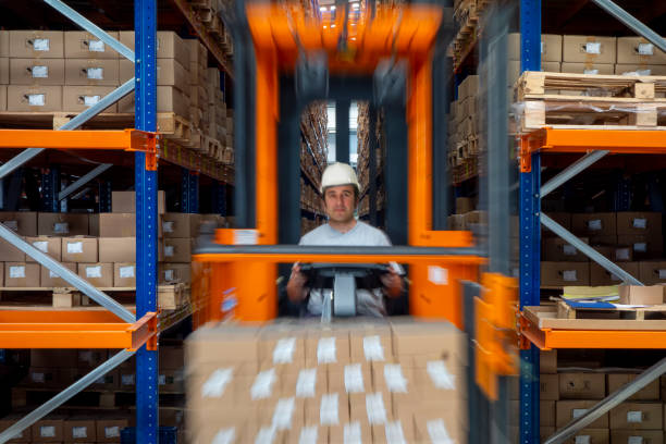 istock Worker moving products with a forklift in a large warehouse. 1975824404