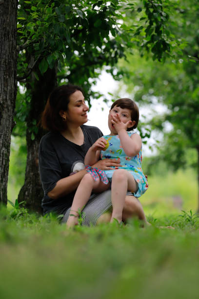 istock mother daughter sitting under the tree 1975829122