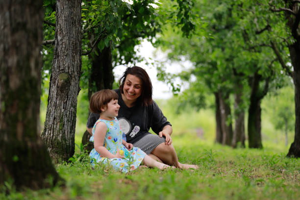 istock mother daughter sitting under the tree 1975831745
