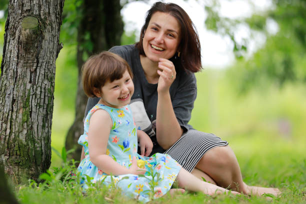 istock mother daughter sitting under the tree 1975832269