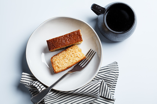 Pieces of breakfast citrus pound cake and a cup of coffee, white background.
