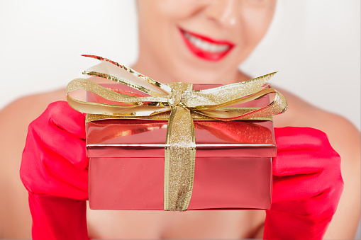 Woman in Red Gloves Giving a Gift and Smiling on a White Background