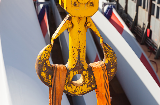 Large yellow double sided cargo crane hook with load straps on it under load.