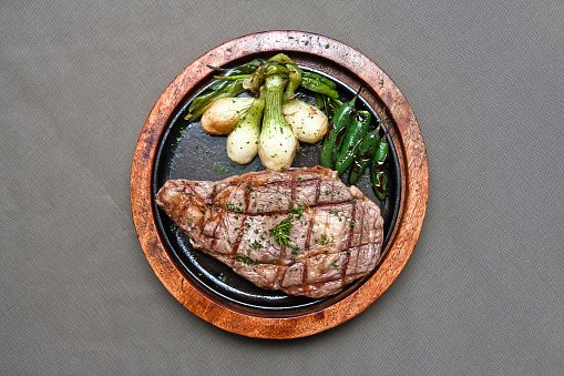 Grilled beef steak with serrano peppers and roasted onions Delicious beef steak on gray background, rib eye