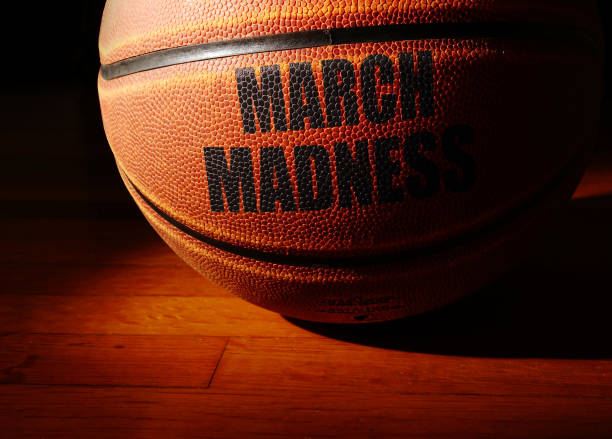 March Madness basketball on a hardwood court, college basketball tournament concept March Madness basketball on a hardwood court, college basketball tournament concept college basketball court stock pictures, royalty-free photos & images