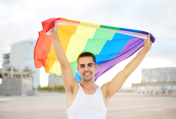 Beautiful gay man with a pride flag. Fighting for his rights. LGBT Concept