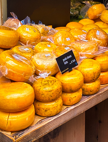 Stacks of traditional Gouda Cheese with herbs are offered for sale at a  market stall on the streets of Amsterdam.