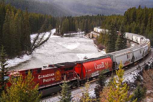 Banff, Alberta, Canada - October 11, 2019:  CP Rail Freight Train Cars at Railway Station with Distant Snowcapped Mountain Peaks of Banff National Park on the Horizon