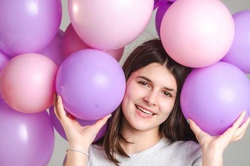 Ready for party. Two girls in stylish summer outfit , paper glasses and air balloons having fun and celebrate birthday.Blue background.