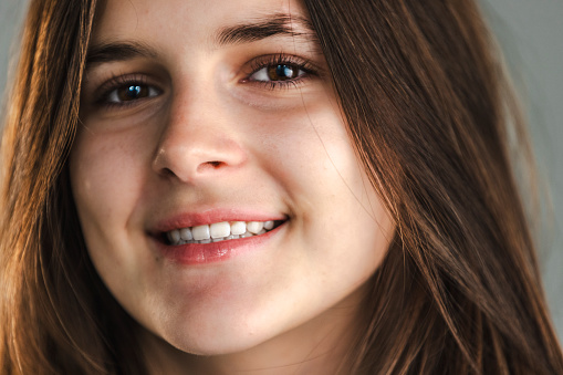 Studio portrait of a teenage girl with long brown hair, wearing a light t-shirt