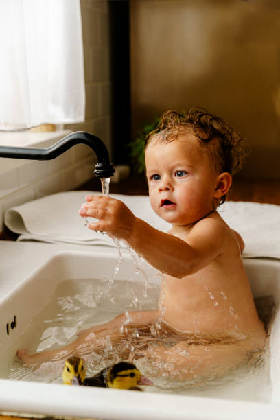istock Baby playing with live ducks swimming around him while bathing in the sink 1975982319