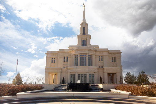 December 24, 2020 - Tucson, Arizona, USA: This is an afternoon view of the exterior of the Tucson Temple, operated by the Church of Jesus Christ of Latter-day Saints.  The central tower and angel Moroni statue are illuminated by a cloud filled sky.