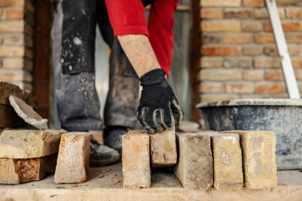 istock Cropped picture of a housebuilder taking brick from a pile while standing on building area. 1976009687