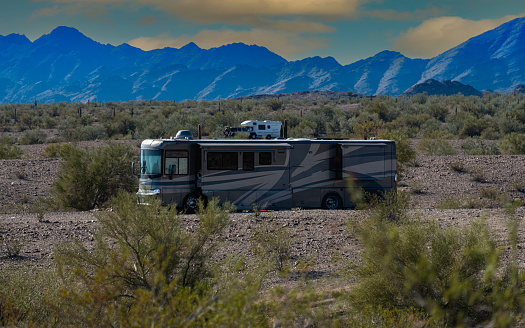 Rv motorhomes parked on state land under mountains and blue cloudy sky