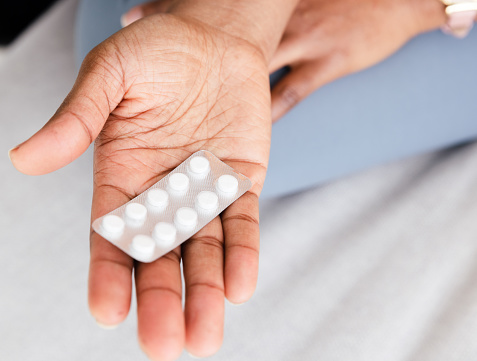Palm hand with one from other white scattering pills. Woman gripes hand with capsules with medicines on light background with copy space.