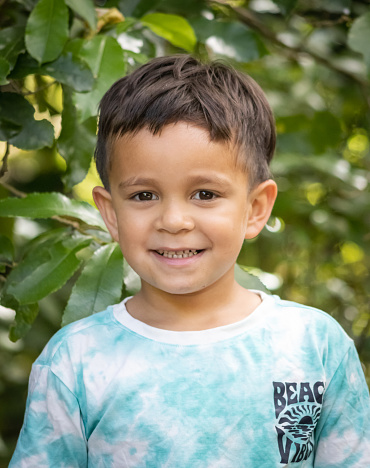 a young Maori boy poses for his portrait in an outdoor setting in New Zealand.