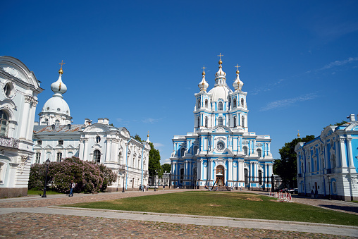Saint Petersburg, Russia - June 08, 2023: Smolny Cathedral built in 1748-1835 as orthodox Voskresensky of all educational institutions, summer sunny day. Unrecognizable people