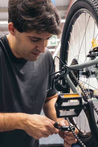 istock vertical portrait bicycle mechanic adjusting chain in workshop 1976058960