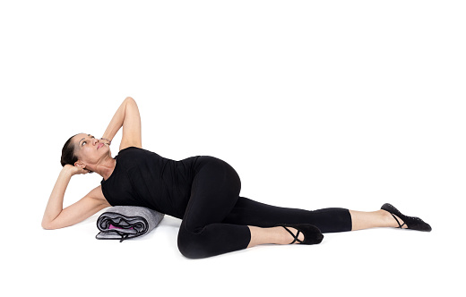 spine rotation variation pose, in the studio isolated on white. Specialized trauma releasing exercises for elderly people, 55 years old woman trainer posing for exercises.