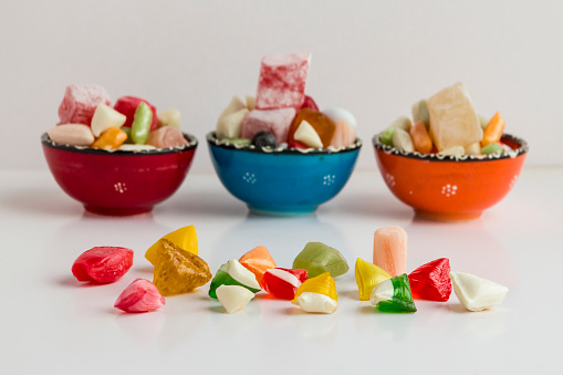 Traditional Turkish hard candy Akide on the line in front of colorful ceramic bowls on white background