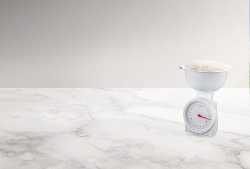 A white food scale with flour in it in a kitchen on a counter top