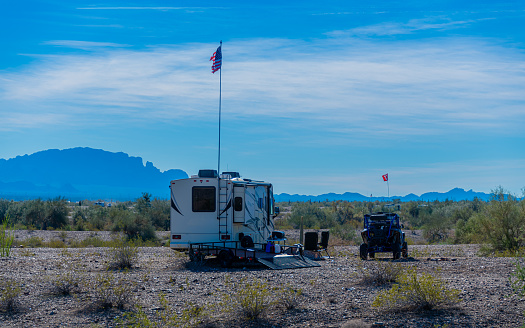 Rv motorhomes parked on state land under mountains and blue cloudy sky with off road vehicle