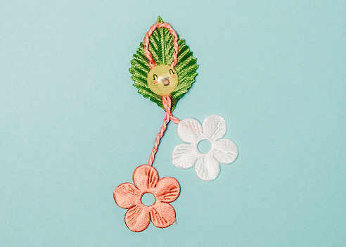 One beautiful homemade martisor made from flowers, a petal and a cheerful smiley face lies in the center on a light blue background, flat lay close-up.