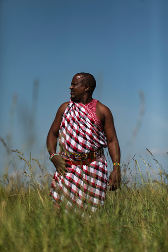 An African tourist guide is standing outside on the field