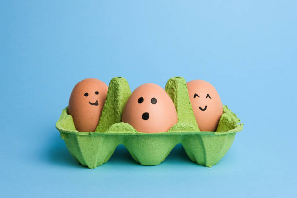 istock Cute easter eggs with funny faces in green box isolated on light blue background. Happy easter concept 1976154971