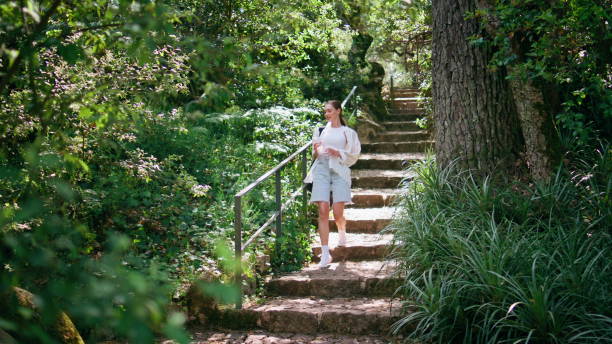 istock Girl going downstairs forest trail with backpack contemplating nature beauty. 1976173768