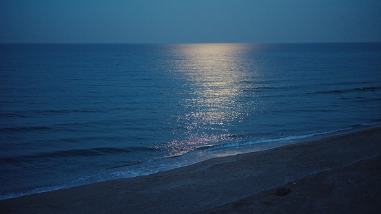 Full moon in the blue hour over calm sea waters. Zen like waterscape.