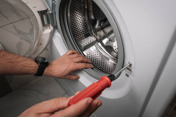 istock a man with a screwdriver disassembles a washing machine. Technician repairing a washing machine 1976186780