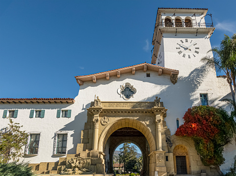 Santa Barbara, CA, USA - November 30, 2023: Santa Barbara County Courthouse monumental great arch set in white stone and tower against blue sky.
