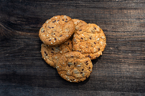 oatmeal thin round cookies with lots of sesame seeds, delicious cookies with white sesame seeds on wooden table and wooden kitchen appliances. oatmeal cookies with seeds on a wooden table