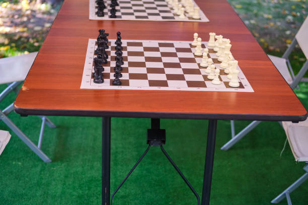 Wooden table with chess pieces on it in the park, closeup