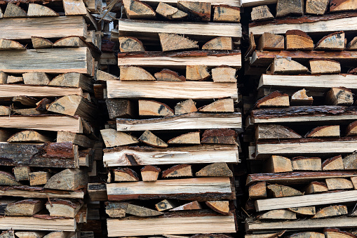 Woodpile lies in a heap, chopped for burning in furnace. Finely chopped and stacked firewood, background. Laid dry firewood, texture, background. Firewood wall, dry chopped firewood background.